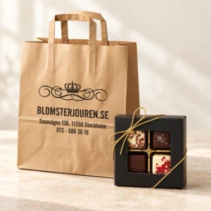 Presentpåse i kraftpapper från Blomsterjouren och en svart chokladask med fyra praliner och guldsnöre.